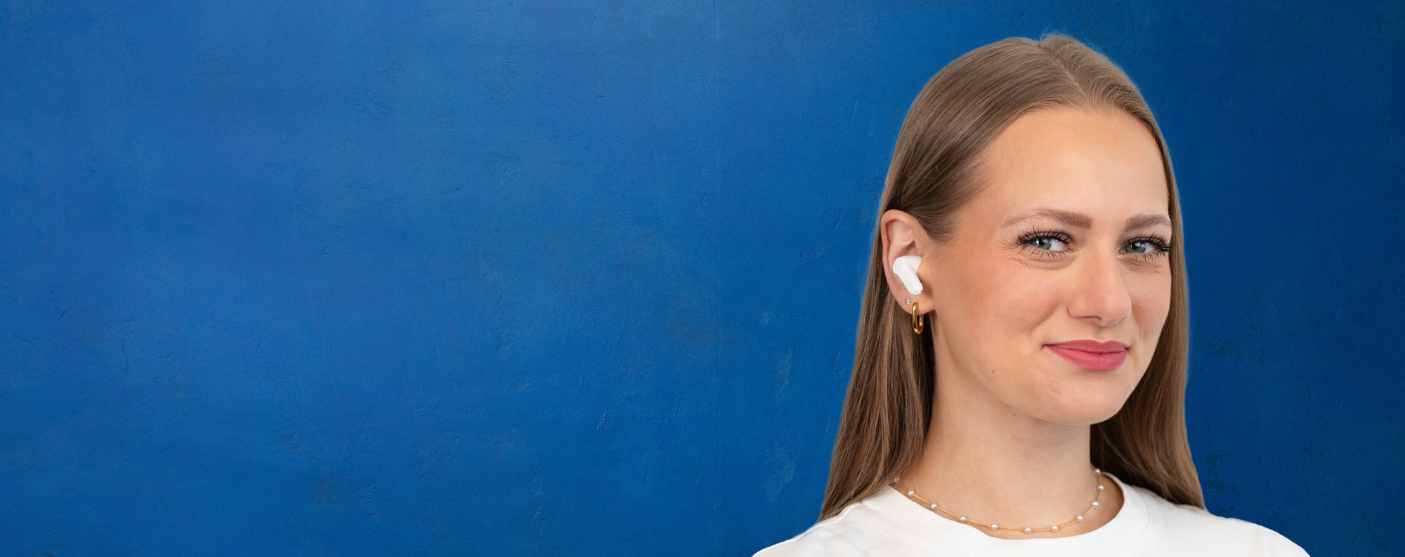 Porträt eines Bankberaters mit In-Ear-Kopfhörern vor blauer Wand